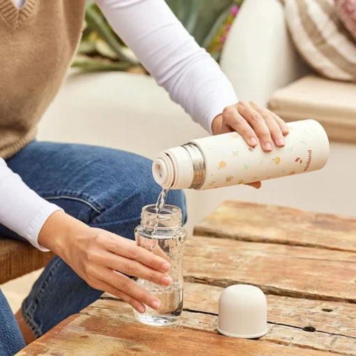 a person pouring water into a glass , thermos miniland